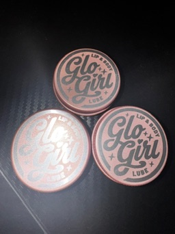 Three Glo Girl tins arranged in a triangle, in cream, gold, and rose.